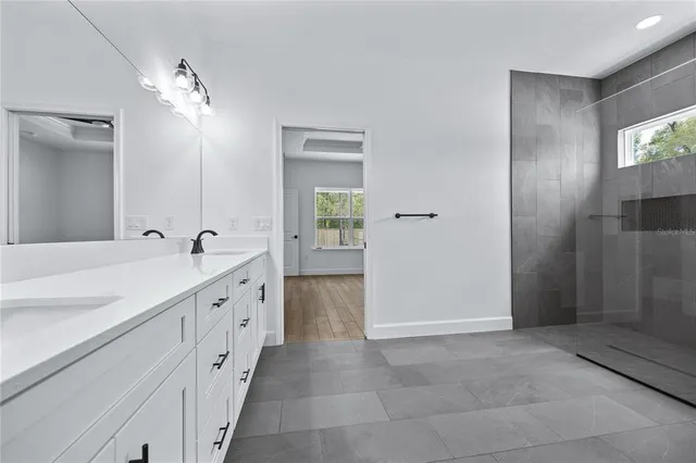 a spacious bathroom with a double vanity sink a large mirror and a shower