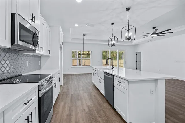 a kitchen with stainless steel appliances granite countertop a sink a stove top oven a counter space and cabinets