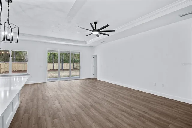 an empty room with wooden floor and chandelier fan