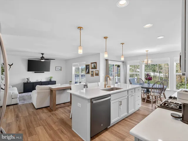 a kitchen with stainless steel appliances a stove a sink a refrigerator a microwave oven a dining table and chairs with wooden floor