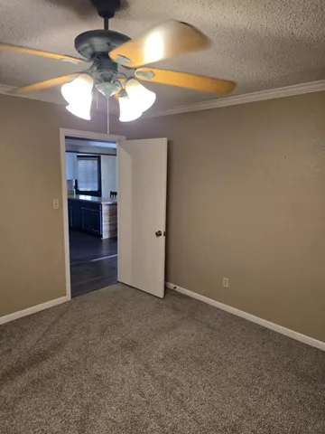 an empty room with a chandelier fan and windows