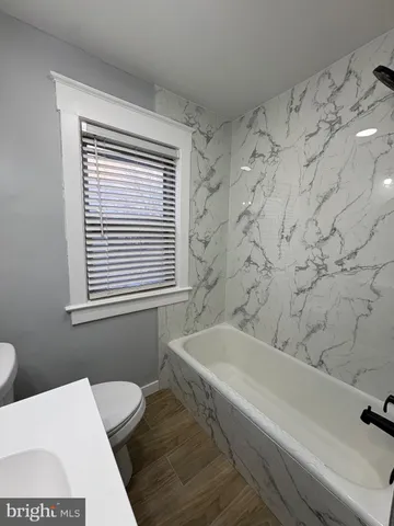 a bath tub sitting next to a white sink and a toilet