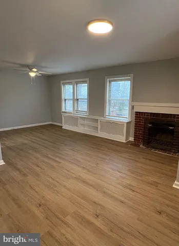 an empty room with wooden floor fireplace and windows