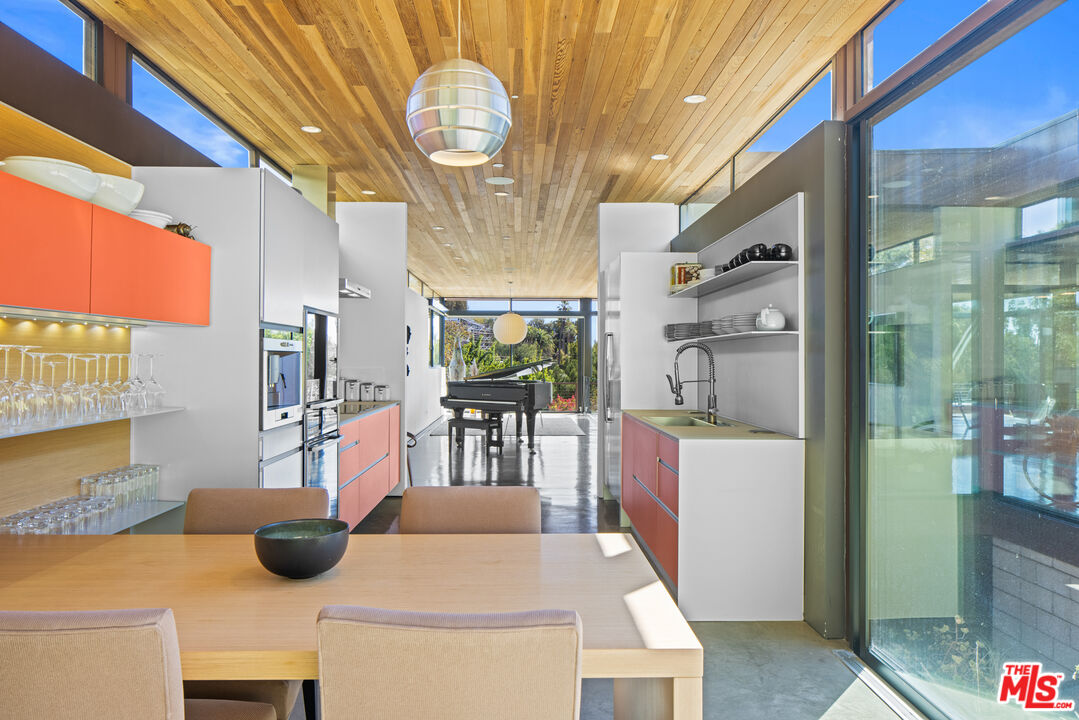 12321 Rochedale Lane Los Angeles, CA 90049 - Photo 20 of 46 a kitchen with stainless steel appliances kitchen island granite countertop a table chairs and a wooden cabinets