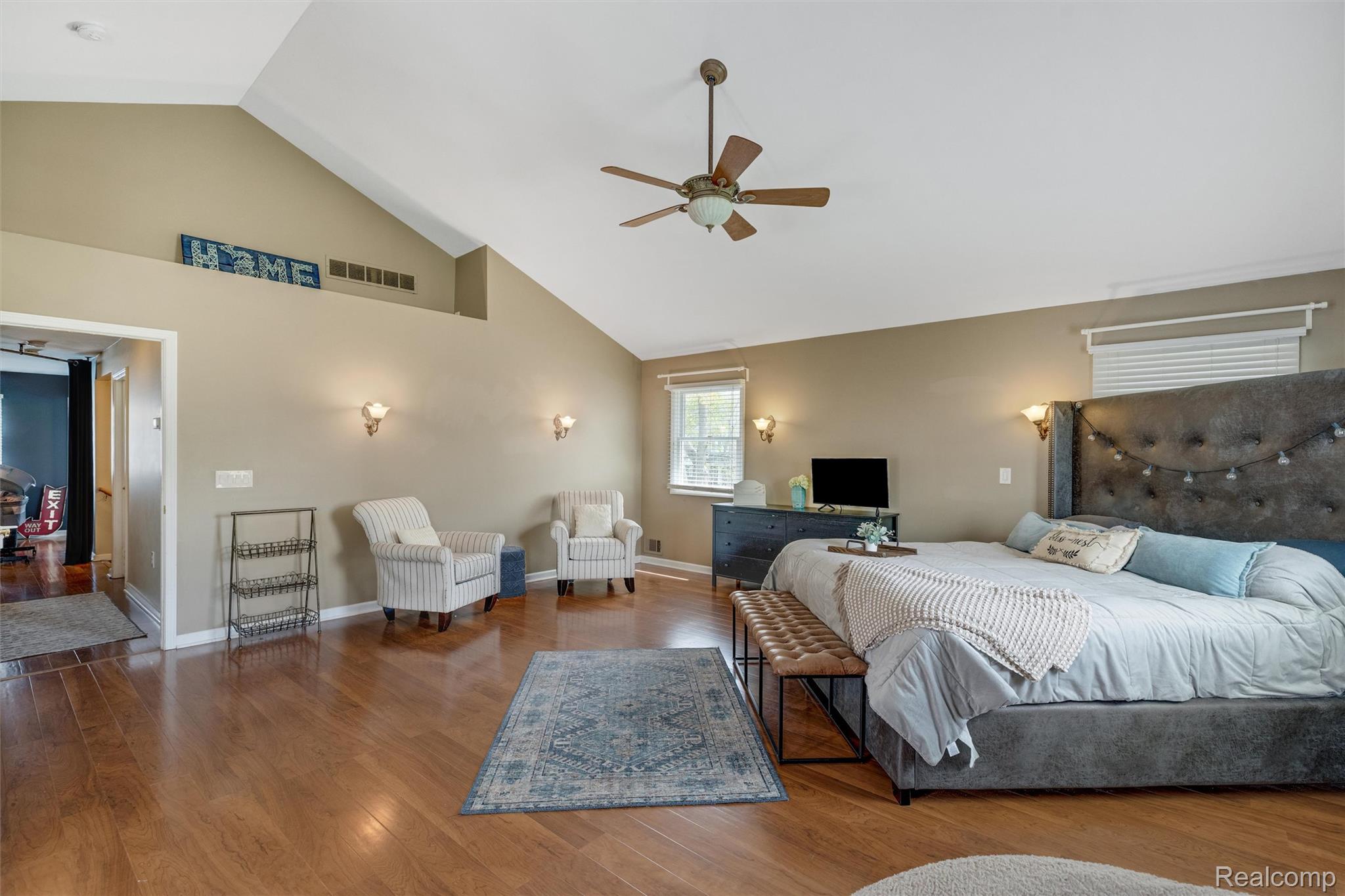 415 Leon Road Walled Lake, MI 48390 - Photo 32 of 47 Vaulted ceilings highlight this expansive room featuring wood-finish flooring, a ceiling fan, and sconce lighting
