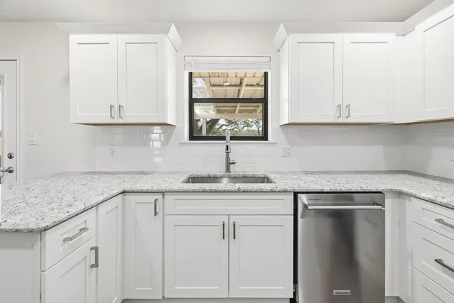 a kitchen with white cabinets appliances and a sink