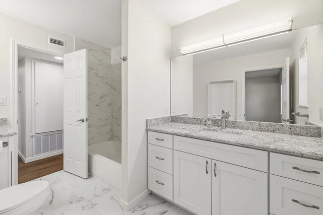 a bathroom with a granite countertop sink a mirror and a shower