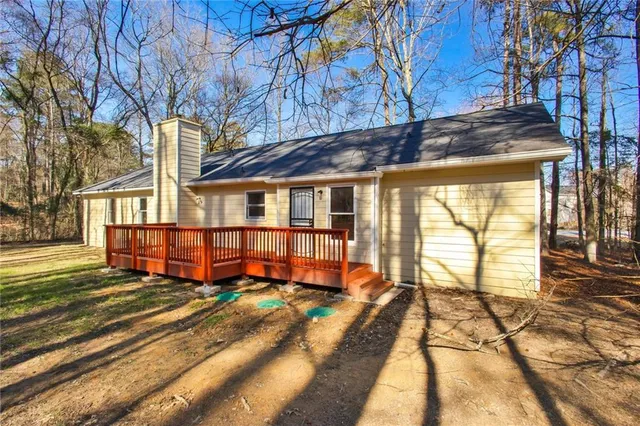 a view of a house with a large window and a yard with table and chairs under an umbrella