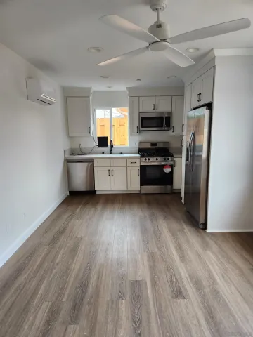 a kitchen with stainless steel appliances a refrigerator a sink dishwasher a stove and white cabinets with wooden floor