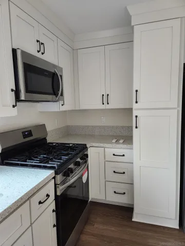a kitchen with stainless steel appliances white cabinets and a stove a oven with wooden floor