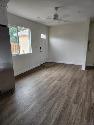 an empty room with wooden floor chandelier fan and windows