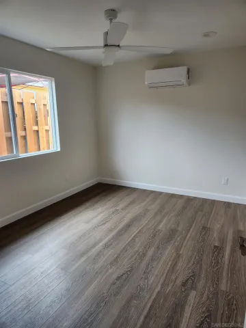 an empty room with wooden floor fan and windows