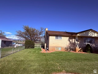 588 North 4500 West West Point, UT 84015 - Photo 50 of 61 Expansive side yard featuring a chain-link fence, mature tree, and a two-story residence with a brick and stucco exterior