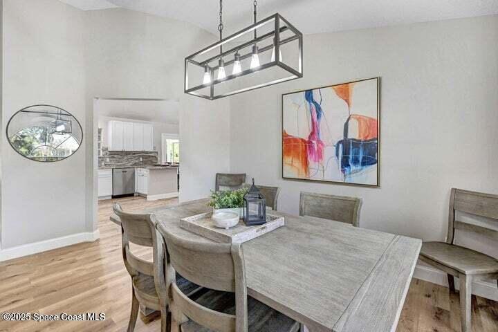 3360 Holly Springs Road Melbourne, FL 32934 - Photo 6 of 30 a view of a dining room with furniture a chandelier and wooden floor