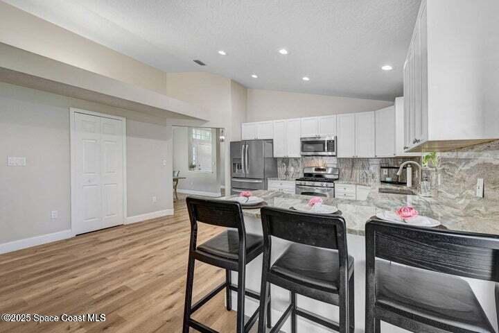 3360 Holly Springs Road Melbourne, FL 32934 - Photo 7 of 30 a kitchen with a dining table chairs and white cabinets