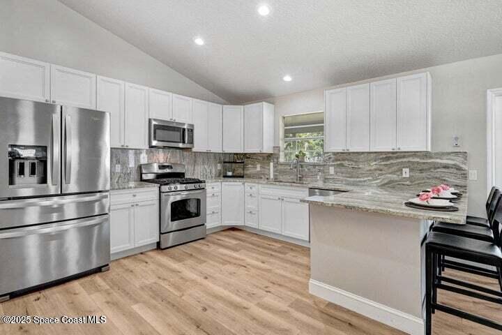3360 Holly Springs Road Melbourne, FL 32934 - Photo 8 of 30 a kitchen with kitchen island a white cabinets and stainless steel appliances