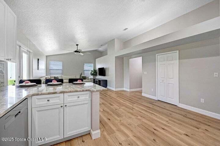 3360 Holly Springs Road Melbourne, FL 32934 - Photo 10 of 30 a large kitchen with kitchen island white cabinets and stainless steel appliances
