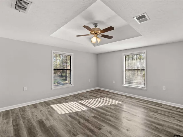 a view of an empty room with a window and wooden floor