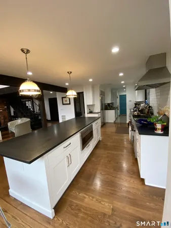 a large kitchen with stainless steel appliances kitchen island a large counter top a stove a chimney a sink and a large window