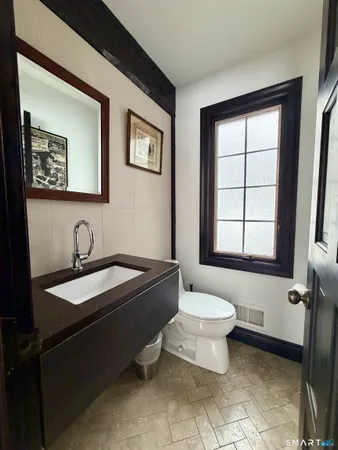a bathroom with a granite countertop sink toilet a mirror and window