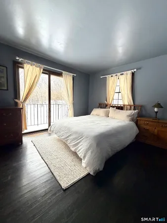 a bedroom with a bed wooden floor and a large window