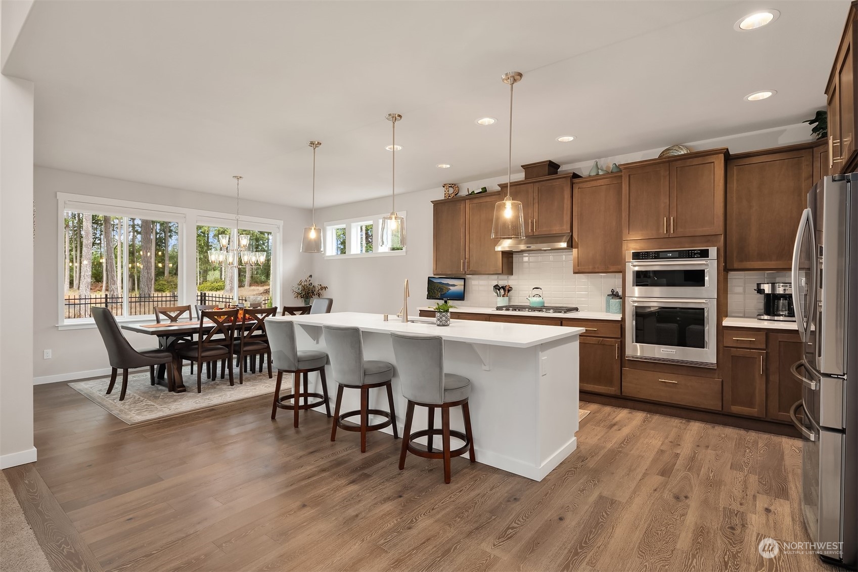 4331 Caddyshack Drive Northeast Lacey, WA 98516 - Photo 6 of 34 a kitchen with stainless steel appliances granite countertop a stove a refrigerator a kitchen island a dining table and chairs with wooden floor