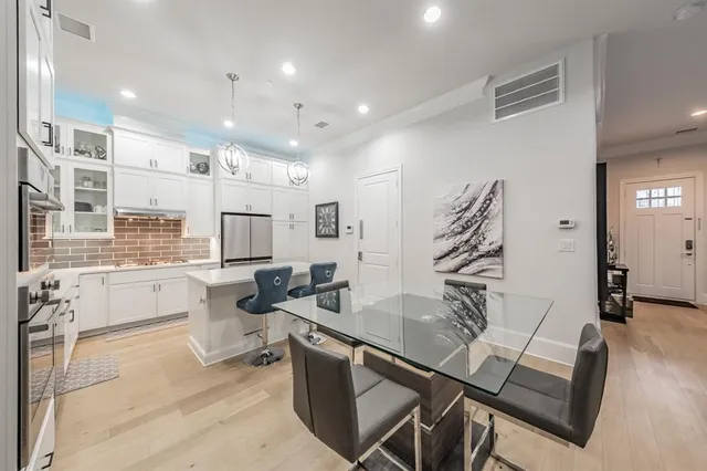 a kitchen with stainless steel appliances granite countertop a stove a refrigerator a oven and white cabinets with wooden floor