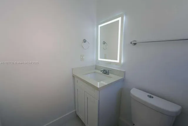 a bathroom with a granite countertop toilet sink and mirror