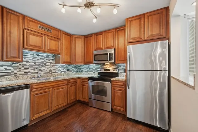 a kitchen with granite countertop wooden cabinets stainless steel appliances and a sink