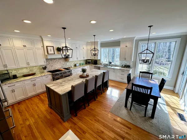 a large kitchen with stainless steel appliances granite countertop a stove a sink dishwasher a dining table and chairs with wooden floor