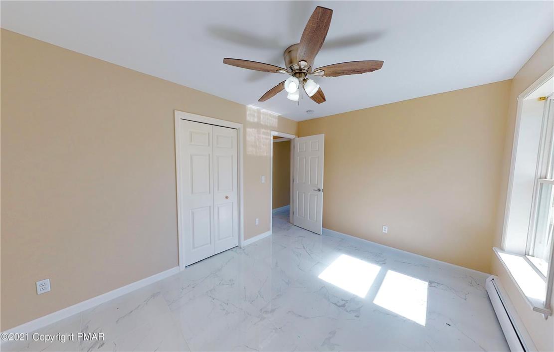 1110 Misty Ridge East Stroudsburg, PA 18302 - Photo 33 of 43 A quiet bedroom showcases a ceiling fan and elegant tile flooring, offering a perfect retreat.