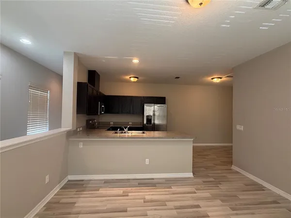 a view of a kitchen with kitchen island a sink wooden floor and a counter top space