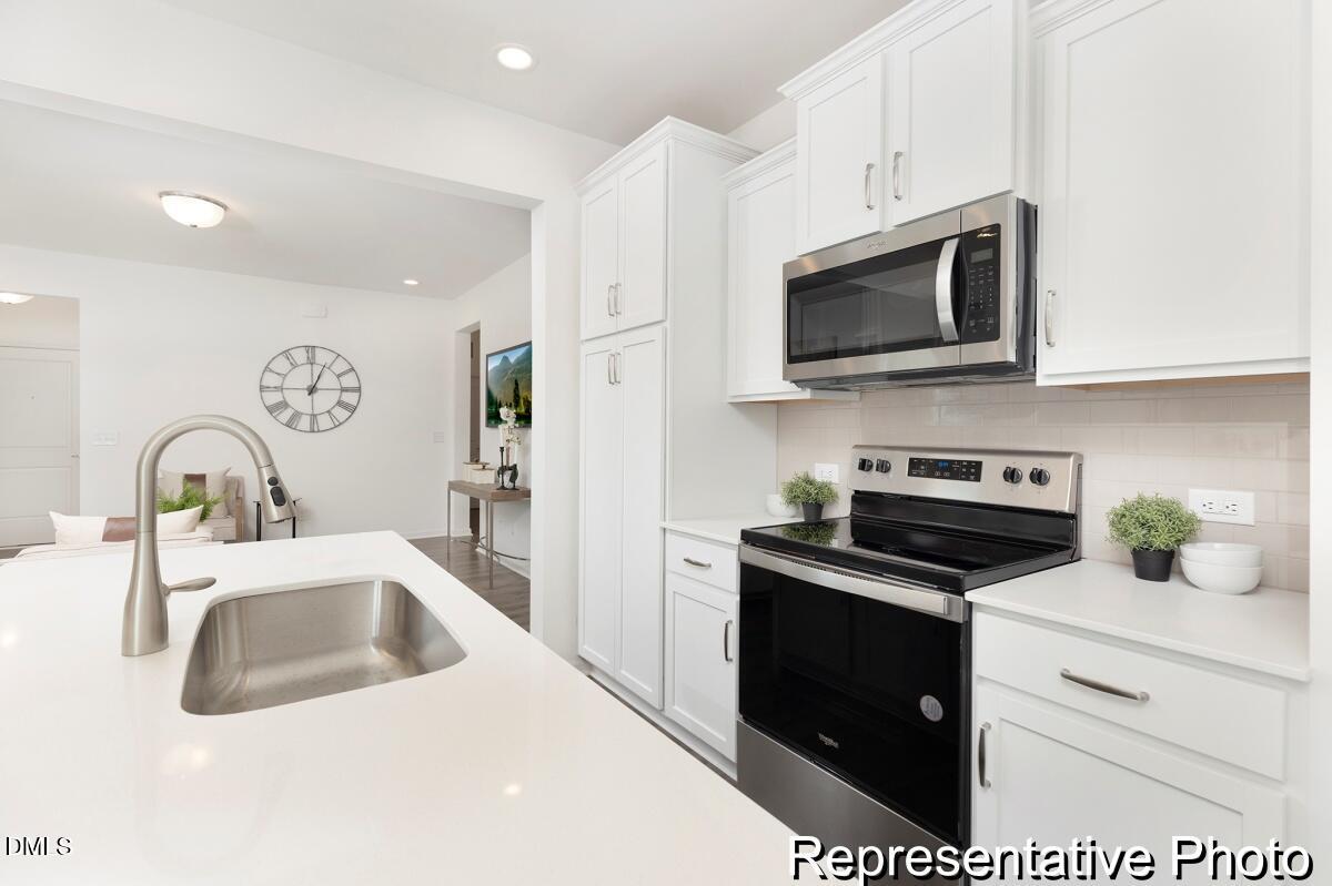 81 Cedarbranch Way, Unit 186P Dunn, NC 28334 - Photo 5 of 15 a kitchen with stainless steel appliances granite countertop a sink a stove a microwave and refrigerator