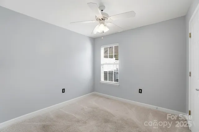 an empty room with windows and chandelier fan