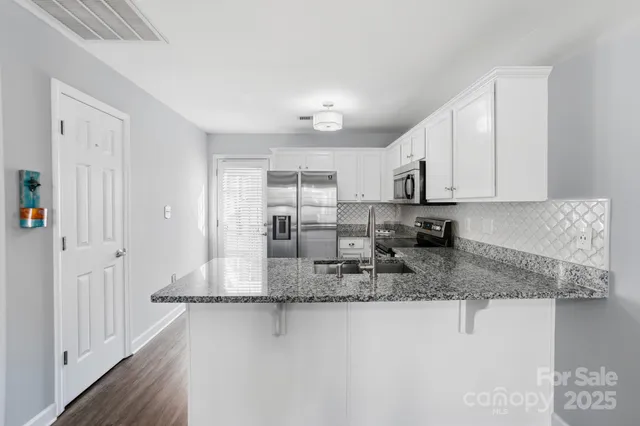 a kitchen with stainless steel appliances granite countertop a sink refrigerator stove and white cabinets