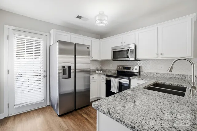 a kitchen with granite countertop a refrigerator and a stove top oven