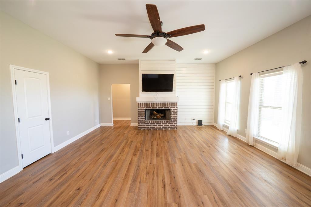 132 Addie Way Tuscola, TX 79562 - Photo 5 of 37 a view of a livingroom with a fireplace a ceiling fan and wooden floor