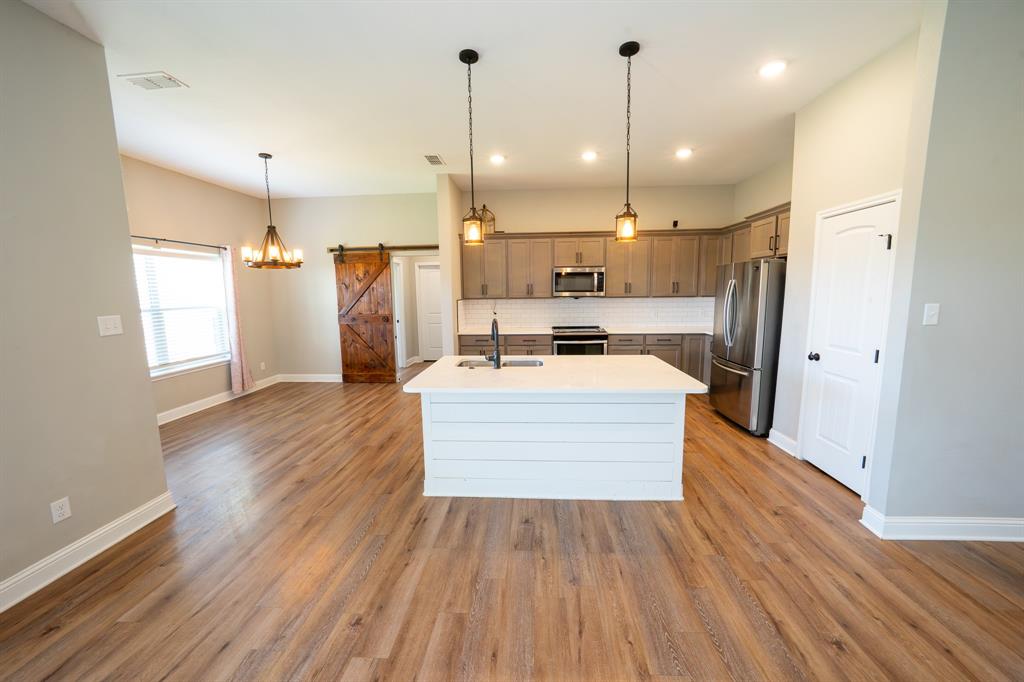 132 Addie Way Tuscola, TX 79562 - Photo 8 of 37 a large kitchen with stainless steel appliances a large counter top a sink a refrigerator and a window
