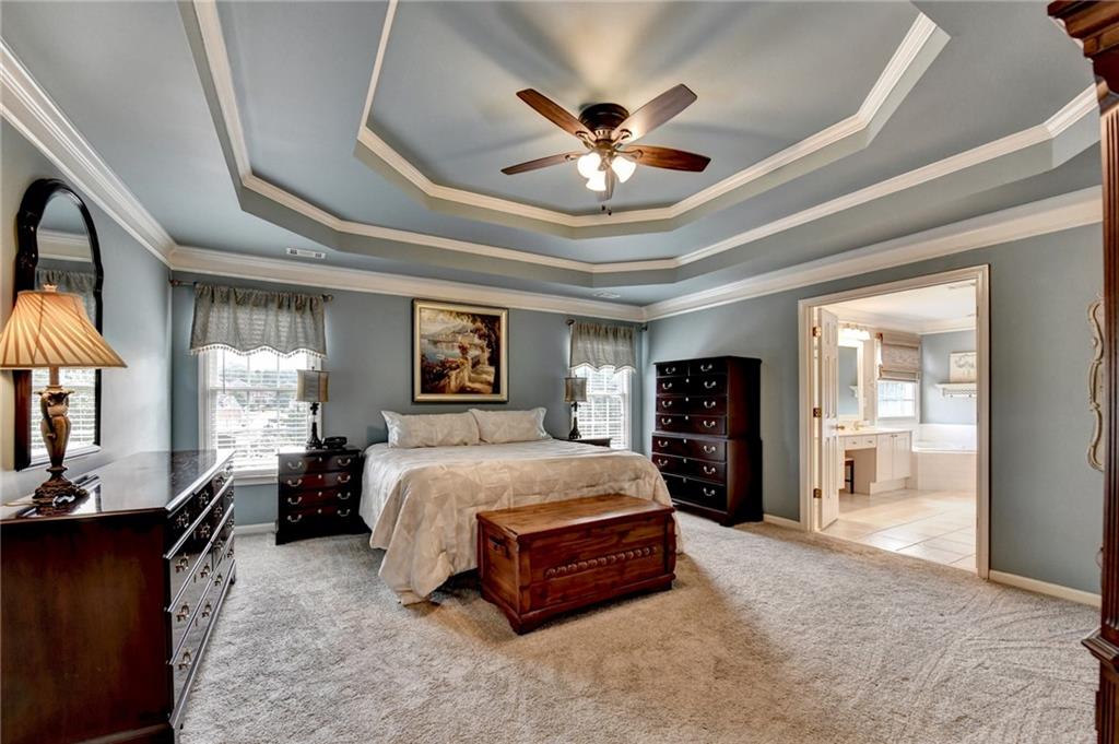 964 Fairview Club Circle Dacula, GA 30019 - Photo 18 of 47 a spacious bedroom with a large bed a chandelier and dresser