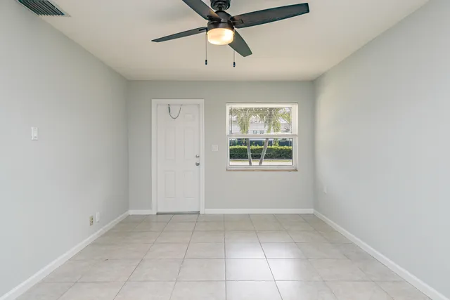 an empty room with windows and fan