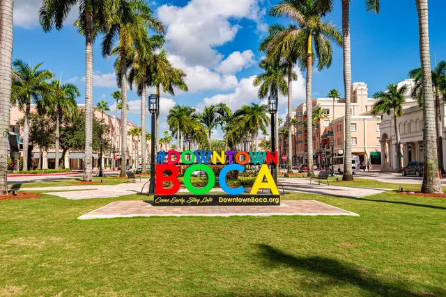 a view of a swimming pool with a lawn chairs under palm trees