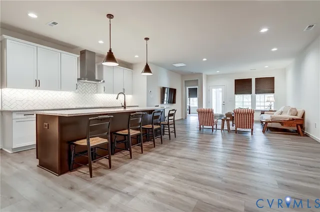 a open kitchen with stainless steel appliances granite countertop a stove a refrigerator a kitchen island a dining table and chairs with wooden floor