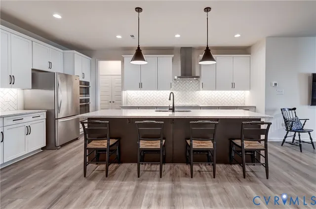 a kitchen with granite countertop a table chairs stove refrigerator and wooden floor