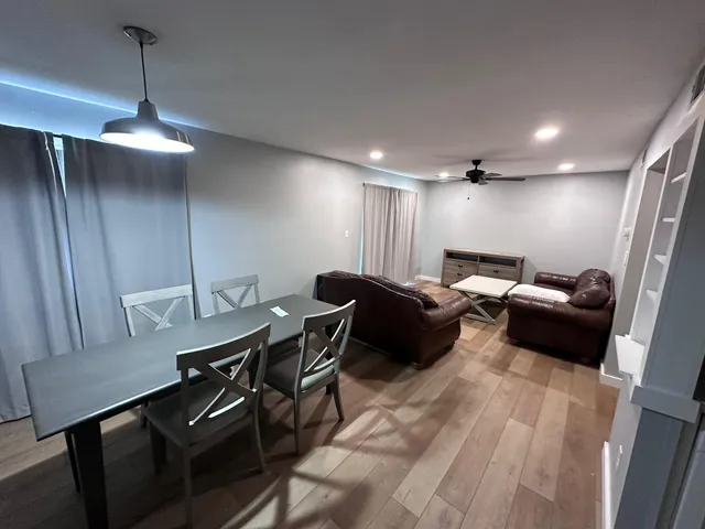 a living room with furniture a ceiling fan and a wooden floor