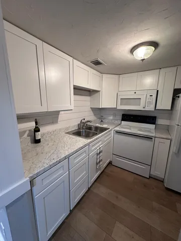 a kitchen with granite countertop white cabinets and white appliances