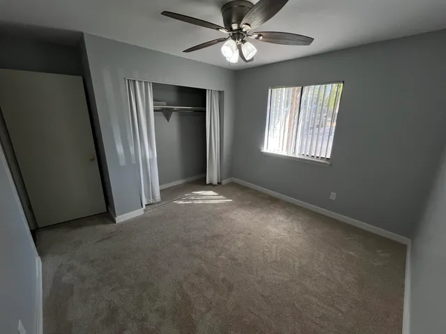 an empty room with windows and fan