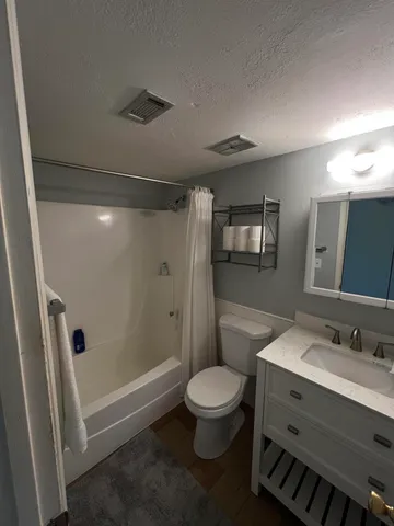 a bathroom with a sink a toilet a mirror and shower