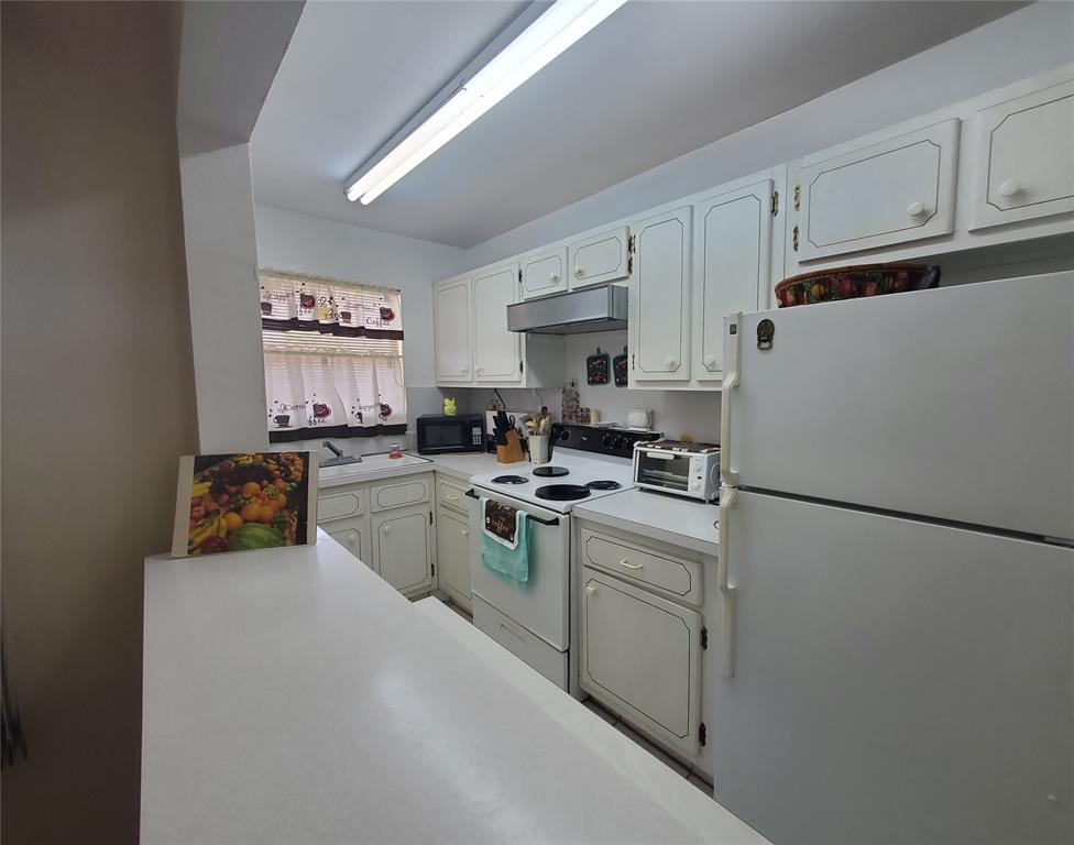 5300 Washington Street, Unit 114C Hollywood, FL 33021 - Photo 6 of 25 a kitchen with a refrigerator a stove a sink and white cabinets