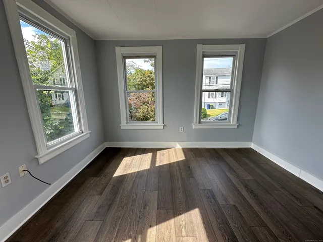 a view of an empty room and wooden floor and window