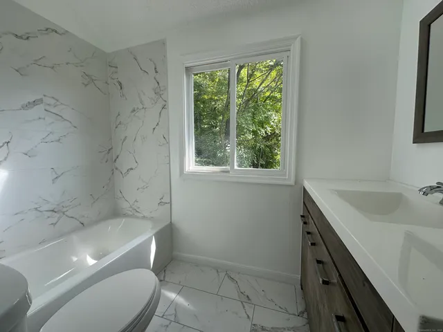 a bathroom with a granite countertop sink toilet and shower